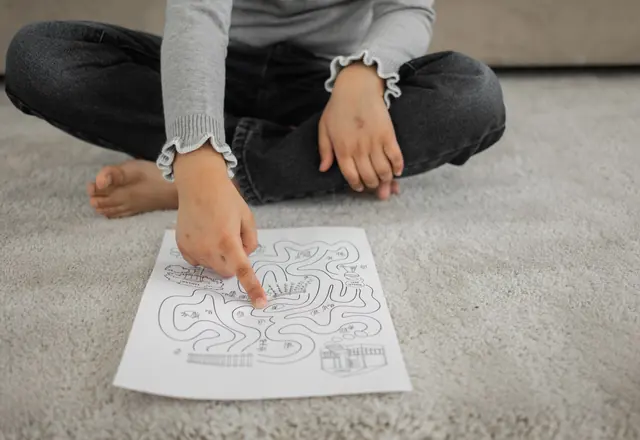 Child tracing a path through a maze with a finger