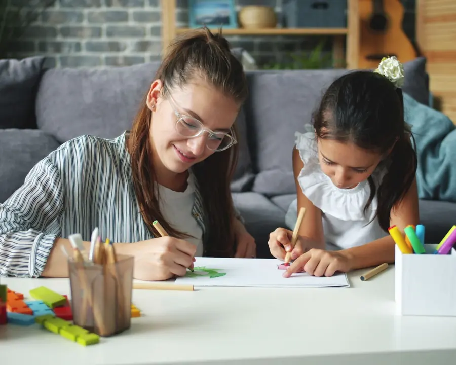 Mother and daughter drawing together at a coffee table
