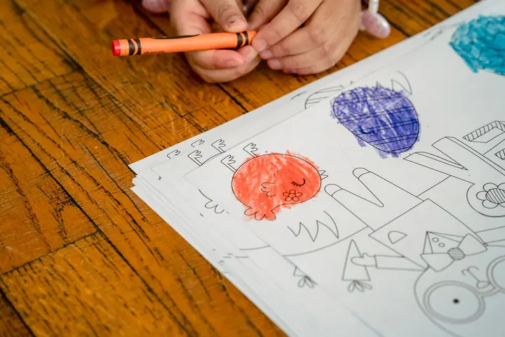 Printed activity pages with a crayon on a wooden table