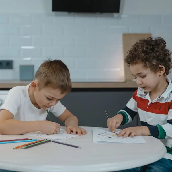 Two boys coloring pages at a kitchen table